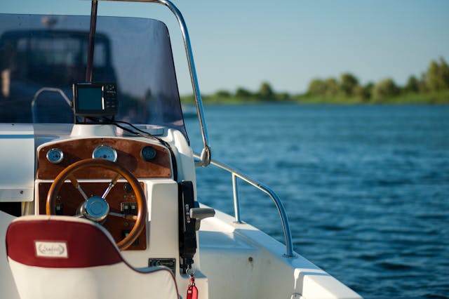 a white boat with a brown steering wheel on the lake